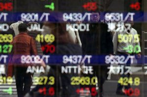 Pedestrians are reflected on an electronic stock at a securities firm in Tokyo Wednesday, March 16, 2016. Asian markets were mixed Wednesday as investors watched for news from a U.S. Federal Reserve policy meeting and from China's annual legislative session. (AP Photo/Eugene Hoshiko)