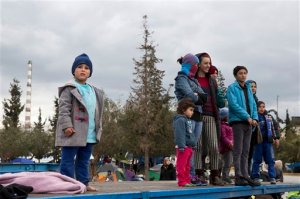 Migrants on a trailer look on as U.S. actress Angelina Jolie leaves from the port of Piraeus near Athens, on Wednesday, March 16, 2016. Jolie spoke Wednesday with refugees in Piraeus, where about 4,000 people are stuck, waiting either to head north to Greeces closed border with Macedonia, or for a place in rapidly-filling official shelters. (AP Photo/Petros Giannakouris)
