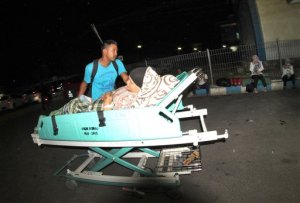 A man pushes a relative who lies on a hospital bed as they were told to leave the building following an earthquake, at a hospital in Padang, West Sumatra, Indonesia, Wednesday, March 2, 2016. Indonesia lifted a tsunami warning issued Wednesday after a powerful earthquake off Sumatra sent islanders rushing to high ground. The U.S. Geological Service said the earthquake had a magnitude of 7.8. (AP Photo/Rivo Andries)