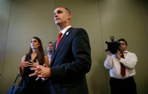 In this photo taken Aug. 25, 2015, Republican presidential candidate Donald Trump's campaign manager Corey Lewandowski watches as Trump speaks in Dubuque, Iowa. Florida police have charged Lewandowski with simple battery in connection with an incident earlier in the month involving a reporter. (AP Photo/Charlie Neibergall)