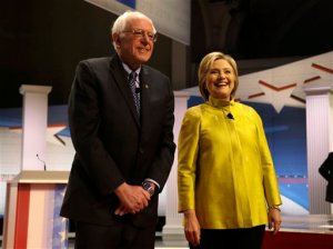 FILE - In this Feb. 11, 2016 file photo, Democratic presidential candidates Sen. Bernie Sanders, I-Vt, left, and Hillary Clinton smile as they take the stage before a Democratic presidential primary debate at the University of Wisconsin-Milwaukee, in Milwaukee. Clinton and Sanders are putting the global economy at the center of their pitch to Democrats, trading charges about who would best represent American workers as their presidential campaign shifts to a series of Rust Belt primaries. Clinton plans to deliver a policy address Friday, March 4, 2016, in Detroit outlining ways to remove economic barriers for families, giving her the opportunity to respond to Sanders, who has accused her of supporting trade deals that have had "disastrous" consequences for workers. (AP Photo/Tom Lynn, File)