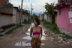 In this Jan. 29, 2016 photo, Tamires da Costa, 16, who's four months pregnant, stands in a street with standing flood water next to her home in the Parque Sao Bento shantytown of Rio de Janeiro, Brazil. Thanks to Aedes aegypti modquito, the Zika virus quickly spread across Brazil and to more than 20 countries in the region, the Caribbean and beyond, leading the World Health Organization this week to declare an international emergency. Brazilian authorities say they have detected a spike in cases of microcephaly, which leaves infants with unusually small heads and can result in brain damage and a host of developmental and health problems. However, the link between Zika and microcephaly is as yet unproven. (AP Photo/Leo Correa)
