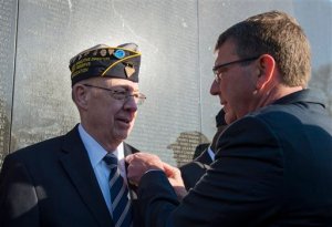 Defense Secretary Ash Carter honors Vietnam Veteran Thomas Snee, who served in the Navy, with a commemorative pin to mark the 50th anniversary of the Vietnam War at the Vietnam Memorial Wall in Washington, Tuesday, March 29, 2016.  (AP Photo/Molly Riley)