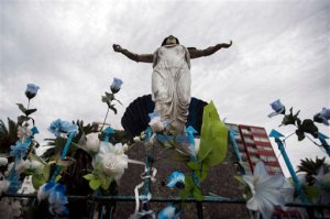 In this April 1, 2016 photo, artificial flowers adorn the base of a statue of Yemanja, the African goddess of the seas, along a promenade in Montevideo, Uruguay. The Catholic Church recently proposed erecting a statue of the Virgin Mary in a park next to a popular promenade, a debate erupted over whether religious symbols in public places violate the separation between church and state. Supporters of erecting the Virgin Mary statue in a public place note that the Uruguayan capital has a statue for Yemanja. (AP Photo/Matilde Campodonico)