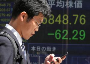 A man walks by an electronic stock board of a securities firm in Tokyo, Friday, April 15, 2016. Asian stocks mostly edged lower on Friday as investors assessed a report on Chinese quarterly economic growth while Japanese shares dropped after an earthquake. Market players were also watching for cues on currencies and other policies from a meeting in Washington, D.C., of financial ministers and central bank governors of the Group of 20 leading industrial nations. (AP Photo/Koji Sasahara)