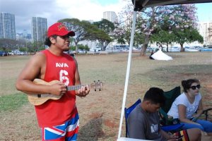 In this Tuesday, April 19, 2016 photo, Henry Maumalanga, left, plays ukulele while hanging out with friends at a park in Honolulu, Hawaii. The agency that promotes travel to Hawaii is starting an online video campaign to remind locals about the benefits of tourism, the states biggest employer. (AP Photo/Audrey McAvoy)