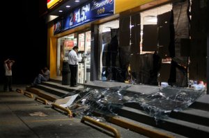 A security guard protects a store that was damaged by the shock waves of an explosion at a State oil company Petroleos Mexicanos' petrochemical plant in Coatzacoalcos, Mexico, Wednesday April 20, 2016. An explosion ripped through a petrochemical plant on the southern coast of the Gulf of Mexico on Wednesday, killing 3 people, injuring dozens and sending flames and a toxin-filled cloud into the air, officials said. (AP Photo/Felix Marquez)