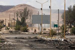 A Russian soldier is seen as smoke rises from a controlled land mine detonation by Russian experts in the ancient town of Palmyra in the central Homs province, Syria, Thursday, April 14, 2016. Russian combat engineers arrived in Syria on a mission to clear mines in Palmyra, which has been recaptured from Islamic State militants in an offensive that has proven Russia's military might in Syria despite a drawdown of its warplanes. (AP Photo/Hassan Ammar)