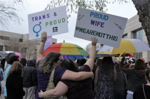 Two protesters hold up signs against passage of legislation in North Carolina, which limits the bathroom options for transgender people, during a rally in Charlotte, N.C., Thursday, March 31, 2016. The rally drew around 100 people at the Charlotte-Mecklenburg Government Center. (AP Photos/Skip Foreman)