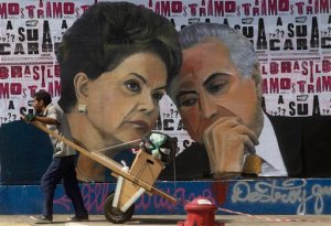A man pushes a cart loaded with garbage for recycling in front of a mural depicting Brazil's President Dilma Rousseff and Vice President Michel Temer, in Sao Paulo, Brazil, Tuesday, April 19, 2016.  Temer who may become Brazils next president is almost as unpopular as Rousseff, and stained by scandals of his own. He signed off on some of the allegedly illegal budget measures that led to the impeachment drive against Rousseff and has been implicated, though never charged, in several corruption investigations. (AP Photo/Andre Penner)