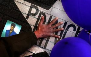 A mourner and fan touches the star for Prince on a wall at First Avenue where the singer often performed, Saturday, April 23, 2016, in Minneapolis. The pop superstar died Thursday at the age of 57. (Jim Gehrz /Star Tribune via AP) MANDATORY CREDIT; ST. PAUL PIONEER PRESS OUT; MAGS OUT; TWIN CITIES LOCAL TELEVISION OUT