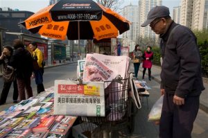 A man looks at a newsstand with a copy of the day's Global Times displayed on a basket in Beijing, China, Tuesday, April 5, 2016. The nationalistic tabloid Global Times published an editorial saying an unidentified "powerful force" was behind the documents leaked from a Panama-based law firm that name relatives of current and retired Chinese politicians, including President Xi Jinping, as owning offshore companies. (AP Photo/Ng Han Guan)