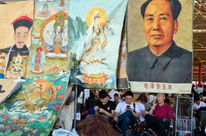 Vendors wait for customers at a curio market near a display of former Chinese leader Mao Zedong alongside images of emperors and deities in Beijing, China, Monday, May 16, 2016. Exactly 50 years ago, China embarked on what was formally known as the Great Proletarian Cultural Revolution, a decade of tumult launched by Mao Zedong to revive communist goals and enforce a radical egalitarianism. The milestone was largely ignored Monday in the Chinese media, reflecting continuing sensitivities about a period that was later declared a "catastrophe." (AP Photo/Ng Han Guan)