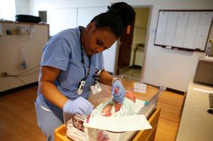 In this Thursday, May 12, 2016, Community Hospital North obstetrician technician Sherron Harris collects a blood sample from newborn Ellie Bailey in the nursery at Community Hospital North in Indianapolis. Ellie is among some 4 million newborns in the United States who will have blood drawn this year to screen them for serious inherited diseases. (AP Photo/Michael Conroy)