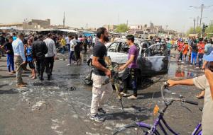 A member of the Kataib Peace Brigades, an Iraqi militia loyal to Shiite cleric Muqtada al-Sadr, center, carries his weapon after a suicide car bombing hit a crowded outdoor market in Baghdad's eastern Shiite neighborhood of Sadr City, Iraq, Tuesday, May 17, 2016. A wave of bombings struck outdoor markets in Shiite-dominated neighborhoods of Baghdad on Tuesday, killing and wounding dozens of civilians, officials said, the latest in deadly militant attacks far from the front lines in the country's north and west where Iraqi forces are battling the Islamic State group. (AP Photo/Karim Kadim)