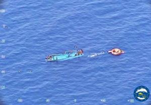 People ask for help after their boat overturned off the Libyan coast Thursday, May 26, 2016.  A migrant boat sank off Libya's coast Thursday with about 100 passengers on board. Officials said 88 people had been rescued and that some 20 bodies were spotted in the sea. (EUNAVFORMED via AP)