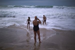 FILE- In this Jan. 1, 2014 file photo, German tourists walk on the seashore as one of them takes a photograph, after swimming in the Atlantic ocean in a beach in Cadiz, southwest Spain. Nudists have lost a seven-year legal battle for access to a popular tourist resort beach on Spain's southwestern tip. (AP Photo/Emilio Morenatti, File)
