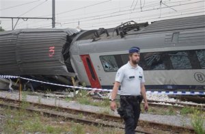 A police officer walks by the wreckage of a passenger and freight train after they collided in Hermalle-sous-Huy, near Liege, Belgium on Monday, June 6, 2016. Belgian media reported several dead and injured as a passenger train struck a freight train. (AP Photo/Virginia Mayo)