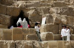 Tourists pose for pictures at the entrance of the Great Pyramid, built by Cheops, known locally as Khufu in Giza, Egypt, Thursday, June 2, 2016. A scientific team scanning the Great Pyramid aimed at discovering the famed pharaonic monument's secrets including possible hidden burial chambers. (AP Photo/Amr Nabil)