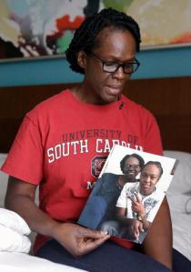 In this Wednesday, June 15, 2016 photo, Andrea Drayton holds a family photo of her and her daughter Deonka Drayton, a victim of the recent mass shootings at the Pulse nightclub in Orlando, Fla. Drayton, her husband, Shepherd, son, Shepherd III, and daughter, Alexia, piled in the family car and began an excruciating early morning journey south from South Carolina to Orlando, where a gunman had opened fire at a gay nightclub killing 49 and wounding scores of others before being killed by police. (AP Photo/John Raoux)