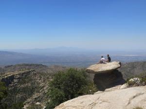 In this Friday, June 3, 2016 photo at Mount Lemmon, just north of Tucson, Ariz., students sit on a large rock overlooking the landscape. Many in Tucson escape to Mount Lemmon as temperatures rise to triple-digits, heading warnings of excessive heat. Mount Lemmon is the highest point in the Santa Catalina Mountains and offers temperatures that are on average 20 degrees cooler than the city. (AP Photo/Astrid Galvan)