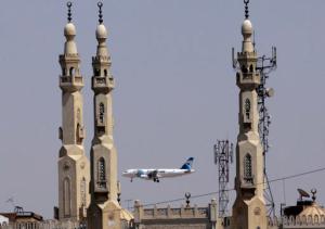 FILE - In this May 21, 2016 file photo, an EgyptAir plane flies past minarets of a mosque as it approaches Cairo International Airport, in Cairo, Egypt. Egyptians officials say a bomb threat has forced an EgyptAir airliner en route to Beijing from Cairo to make an emergency landing in Uzbekistan, where the aircraft is being searched. (AP Photo/Amr Nabil, File)