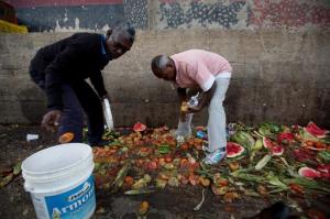 In this May 31, 2016 photo, Pedro Hernandez, left, and his friend Luis Daza, pick up tomatoes from the trash area of the Coche public market in Caracas, Venezuela. At Coche, even once middle class Venezuelans made desperate by the country's economic collapse have taken to sifting through the trash to resell or feed themselves on discarded fruits and vegetables. (AP Photo/Fernando Llano)