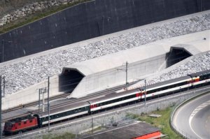 FILE- In this Tuesday, May 31, 2016 file photo, a train passes in front of the northern portal of the Gotthard Base Tunnel on the eve of its inauguration, in Erstfeld, Canton of Uri, Switzerland. Just like Hannibal in ancient times, Swiss engineers have conquered the Alps burrowing the worlds longest railway tunnel to ease trade and congestion in European trade and travel. (Laurent Gillieron/Keystone via AP)
