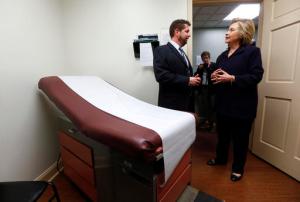 FILE - In this May 2, 2016 file photo, Democratic presidential candidate Hillary Clinton listens to Dr. Christopher Beckett, CEO of Williamson Health and Wellness Center during a tour an exam room of the facility in Williamson, W.Va. With the hourglass running out for his administration, President Barack Obama’s health care law is struggling in many parts of the country. Double-digit premium increases and exits by big-name insurers have caused some to wonder whether “Obamacare” will go down as a failed experiment. (AP Photo/Paul Sancya)