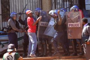 Armed Zimbabwean Riot Police confront a protestor during a demonstration in Harare, Friday, August, 26, 2016. The demonstration organised by opposition political parties calling for reforms is the first time that the fractured opposition has joined forces in a single unified action to confront President Robert Mugabes government. (AP Photo/Tsvangirayi Mukwazhi)