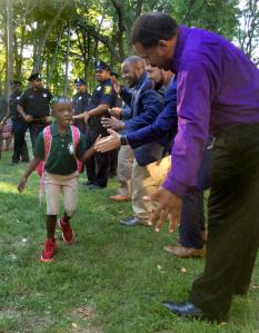 In this Tuesday, Aug. 30, 2016 photo, black professional men from the community greet students arriving for the first day of school at Martin Luther King Jr. Elementary School in Hartford, Conn. Similar welcome ceremonies have been staged for students from minority communities in cities around the country including Atlanta, Boston and Seattle. (AP Photo/Michael Melia)