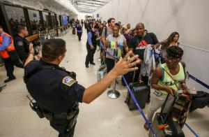 Police officers stand guard as passengers wait in line at Terminal 7 in Los Angeles International Airport, Sunday, Aug. 28, 2016. Reports of a gunman opening fire that turned out to be false caused panicked evacuations at Los Angeles International Airport on Sunday night, while flights to and from the airport saw major delays. Passengers who fled had to be rescreened through security. A search through terminals brought no evidence of a gunman or shots fired, Los Angeles police spokesman Andy Neiman said.  (AP Photo/Ringo H.W. Chiu)