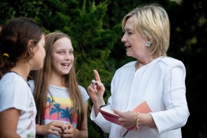 Democratic presidential candidate Hillary Clinton speaks with neighborhood children as she signs a book for them following a fundraiser at a private home in Sagaponack, N.Y., Tuesday, Aug. 30, 2016. (AP Photo/Andrew Harnik)