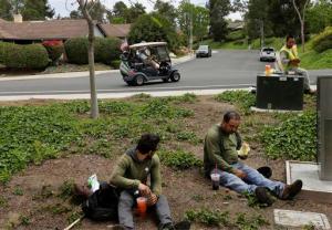 FILE - In this May 4, 2016, file photo, Duncan Wallace drives a golf cart from his house to his golf club as a group of landscape workers take a break in Vista, Calif. Income inequality has surged near levels last seen before the Great Depression. The average income for the top 1 percent of households climbed 7.7 percent last year to $1.36 million, according to tax data. That privileged sliver of the population saw pay climb at almost twice the rate of income growth for the other 99 percent, whose pay averaged a humble $48,768. (AP Photo/Gregory Bull, File)