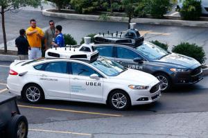 People stand by self-driving Ford Fusion hybrid cars while test driving the vehicles, Thursday, Aug. 18, 2016, in Pittsburgh. Uber said that passengers in Pittsburgh will be able to summon rides in self-driving cars with the touch of a smartphone button in the next several weeks. The high-tech ride-hailing company said that an unspecified number of autonomous Ford Fusions with human backup drivers will pick up passengers just like normal Uber vehicles. Riders will be able to opt in if they want a self-driving car, and rides will be free to those willing to do it, spokesman Matt Kallman said. (AP Photo/Jared Wickerham)