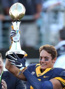 California Golden Bears' Chad Hansen holds the trophy presented to his team after defeating the Hawaii Rainbow Warriors in the opening game of the U.S. college football season at Sydney's Olympic stadium in Sydney, Saturday, Aug. 27, 2016. The last American football of any kind played in Sydney was an NFL preseason game at the Olympic stadium that attracted 73,000 spectators in 1999. (AP Photo/Rick Rycroft)