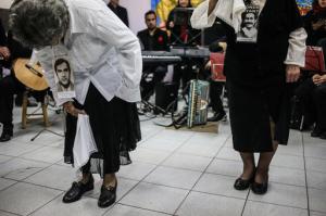 In this Sept. 5, 2016 photo, Violeta Zuniga, right, and Martha Perez, wearing photographs of their respective partners who were disappeared during Gen. Augusto Pinochet’s 1973-1990 rule and holding handkerchiefs, perform Chile's national dance the cueca at a school in Santiago, Chile. The courtship dance was first performed alone in public in 1978 to commemorate International Women’s Day. The handkerchief, which is traditionally used in the cueca, has become a symbol of mourning for the women who continue to search for their disappeared loved ones. (AP Photo/Esteban Felix)