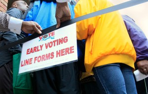 FILE – In this Oct. 2, 2012, file photo, a man places a sign letting people know where to line up for early voting at the Hamilton County Board of Elections in Cincinnati. In Ohio, one of the biggest prizes in the 2016 presidential election, groups have challenged shortened early voting, procedures for absentee and provisional ballots and the process for purging voters from registration rolls, potentially affecting when voters can cast ballots and how ballots are counted. (AP Photo/Al Behrman, File)