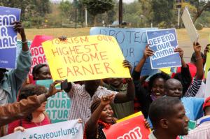Kenyans hold up signs as they attend a protest to protect the Nairobi National Park in Nairobi, Friday, Sept. 16, 2016. Dozens of angry people have marched in the Kenyan capital Nairobi to protest plans to build a railway line over a national park. The protesters included conservationists and others who wore T-shirts and carried banners saying "don't rape our park." (AP Photo/Khalil Senosi)