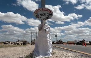 A member of an evangelical organization, "Los Angeles Mensajeros" or Messenger Angels, holds a sign with a message that reads in Spanish; "Chapo Guzman, your mother prays for your soul" in front of the maximum-security prison where Guzman is being held, in Ciudad Juarez, Mexico, Saturday, Sept. 24, 2016. On Monday a hearing is scheduled on the appeal by Guzman against his extradition to the United States. For the past few years the Messenger Angels, who are part of a small local church called Psalm100, have been holding protests against violence and corruption in Juarez dressed as angels. (AP Photo/Christian Torres)