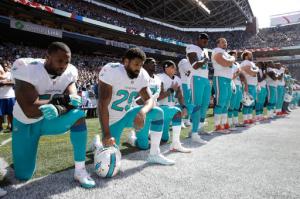 From left, Miami Dolphins' Jelani Jenkins, Arian Foster, Michael Thomas, and Kenny Stills, kneel during the singing of the national anthem before an NFL football game against the Seattle Seahawks, Sunday, Sept. 11, 2016, in Seattle. (AP Photo/Stephen Brashear)