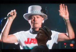 Lead singer Gord Downie is seen performing on a screen as a man watches during a viewing party for the final stop in Kingston, Ontario, from Vancouver, British Columbia, Saturday Aug. 20, 2016. The Tragically Hip mixed fan favourites, newer songs and some politics on Saturday night during the final show of their "Man Machine Poem" tour. (Darryl Dyck/The Canadian Press via AP)