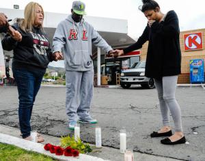 FILE - In this March 14, 2016 file photo, Francine Prieto-Estrada, left, leads Donald Pride and Elisa Castro in a prayer at memorial site for 12-year-old shooting victim Jason Spears at a Circle K in San Bernardino, Calif. His 14-year-old cousin, Terrance Spears, was wounded as the pair walked to the convenience store. San Bernardino has seen a rise in homicides, and Police Chief Jarrod Burguan said homicides could double in 2016 from last year. (Rachel Luna/The Sun via AP, File)
