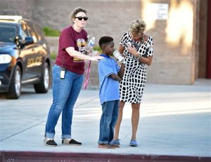 A shoeless student stands with school administrators waiting to be picked up after being released from Walter Johnson Junior High School Wednesday, Sept. 7, 2016, in Las Vegas. Hundreds of anxious parents staked out a Las Vegas middle school after mercury was found and federal officials kept more than a thousand students for up to 17 hours to screen them for exposure to the neurotoxin.. (David Becker/Las Vegas Review-Journal via AP)