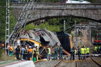 Emergency personnel attend the scene after a passenger train traveling from Vigo to Porto, in neighboring Portugal, derailed in O Porrino, in Spain's northwestern Galicia region, killing and injuring people, authorities said Friday Sept. 9, 2016 . The train had three cars. The front one came completely off the track and hit a post next to the line, leaving it leaning to one side. The back two cars were partly off the tracks. Spanish media said the train was carrying around 60 passengers.(AP Photo/Lalo R. Villar)