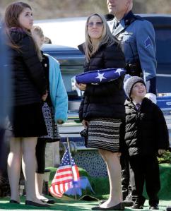 FILE - In this March 22, 2016 file photo, Reisa Clardy, the widow of Mass. State Trooper Thomas L. Clardy, holds a folded flag as she and her children watch balloons fly during his funeral in Hudson, Mass. As Massachusetts voters prepare to decide whether to legalize recreational marijuana use, the widow of a state trooper and father of seven killed when a driver high on marijuana barreled into his cruiser, is making an emotional plea against a ballot question that would legalize recreational marijuana. (AP Photo/Elise Amendola, File)