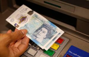 FILE - In this Sept. 13, 2016 file photo, a member of staff at a branch of Halifax bank, in London, displays a new British 5 pound sterling note, made from polymer, which is being launched Tuesday.  The beleaguered British pound plummeted briefly to a fresh 31-year low Friday, Oct. 7, 2016,  amid intensifying concerns about Britain's exit from the European Union. The pound tumbled nearly 6 percent in early Asian trading, falling as low as $1.1789, according to FactSet data.  (AP Photo/Alastair Grant, File)