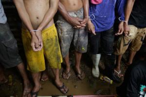 In this Wednesday, Oct. 5, 2016 photo, Filipino men have plastic zip ties on their wrists following a police raid at an alleged drug den as part of the continuing "War on Drugs" campaign of Philippine President Rodrigo Duterte near the Payatas dumpsite in suburban Quezon city, north of Manila, Philippines. In just 100 days in office, Duterte has stirred a hornet's nest by picking a fight with Barack Obama, the United Nations, the European Union and others who have criticized his brutal crackdown against drugs that has left more than 3,600 suspects dead. (AP Photo/Aaron Favila)