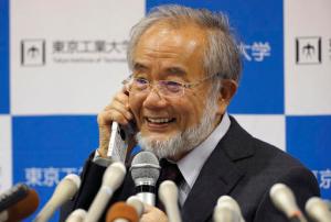 In this Monday, Oct. 3, 2016 photo, Nobel Prize winner Yoshinori Ohsumi smiles as he speaks with Japanese Prime Minister Shinzo Abe on a mobile phone during a press conference at the Tokyo Institute of Technology in Tokyo. Ohsumi won the Nobel Prize in medicine on Monday for discoveries on how cells break down and recycle content, a garbage disposal system that scientists hope to harness in the fight against cancer, Alzheimer’s and other diseases. (AP Photo/Shizuo Kambayashi, File)