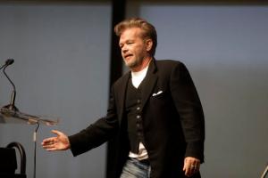 Musician John Mellencamp pays tribute to folk singer John Prine while addressing an audience during PEN New England's Song Lyrics of Literary Excellence Award ceremonies at the John F. Kennedy Library and Museum, Monday, Sept. 19, 2016, in Boston. Tom Waits, his wife, Kathleen Brennan, and Prine were presented with the award during ceremonies Monday. (AP Photo/Steven Senne)